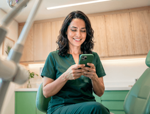 Profissional de saúde sorridente em consultório consultando o celular