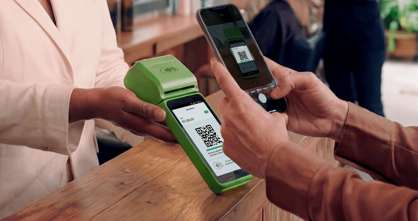 Cliente escaneando QR Code Pix na maquininha Stone com o celular para fazer um pagamento