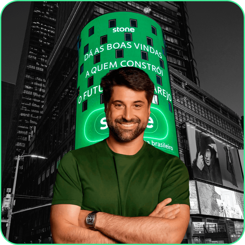Homem sorrindo na frente de um prédio escrito stone