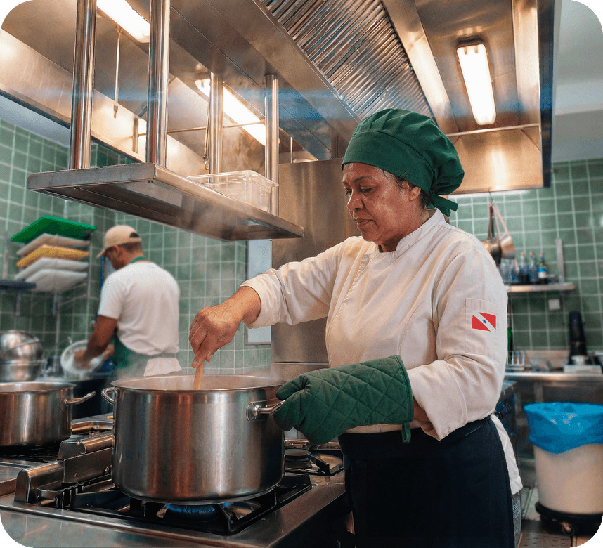 Chef em cozinha de restaurante mexendo uma panela no fogão
