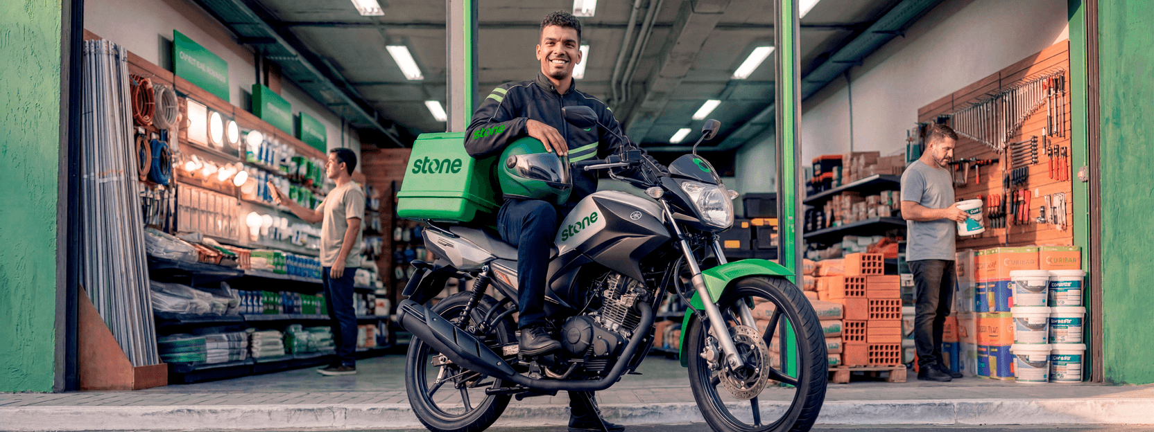 Polo Angel Stone com moto e baú da marca em frente a uma loja