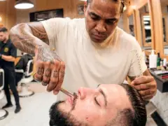 Barbeiro atendendo cliente em sua barbearia