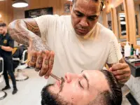 Barbeiro atendendo cliente em sua barbearia