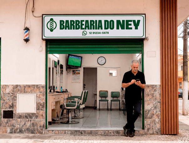 Empreendedor consultando o celular na entrada da Barbearia do Ney