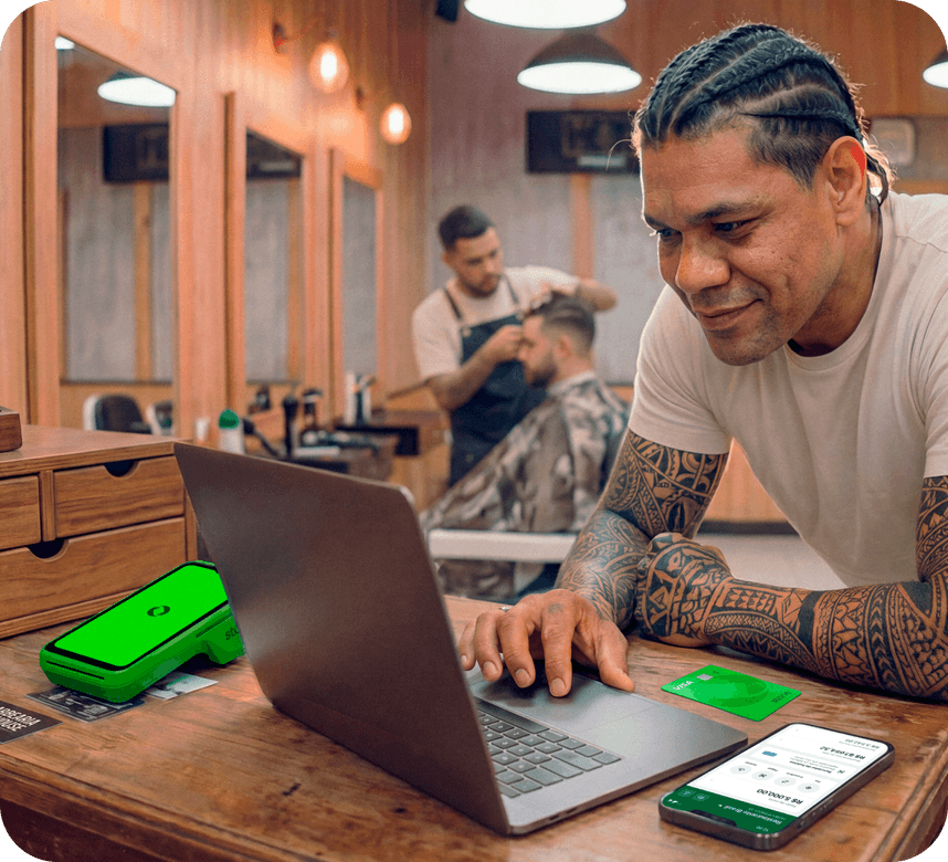 Funcionário em barbearia utilizando um computador junto com a maquininha stone