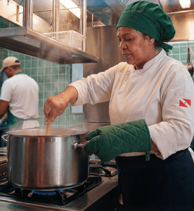 Chef em cozinha de restaurante mexendo uma panela no fogão