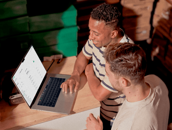 Dois empreendedores analisando dados em um notebook dentro de um armazém