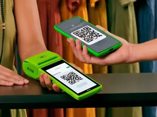 Cliente em loja de roupas pagando por QR Code Pix com o celular escaneando o código na maquininha Stone