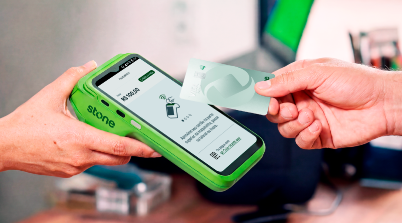 Empreendedora em loja de roupas recebendo pagamento via QR Code Pix na maquininha Stone