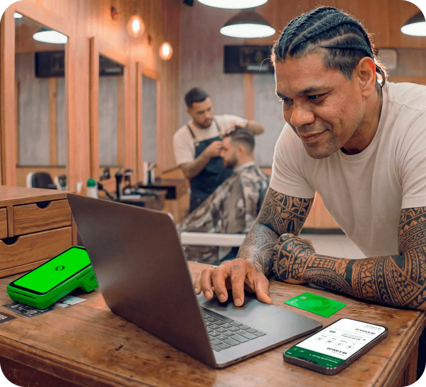Funcionário em barbearia utilizando um computador junto com a maquininha stone