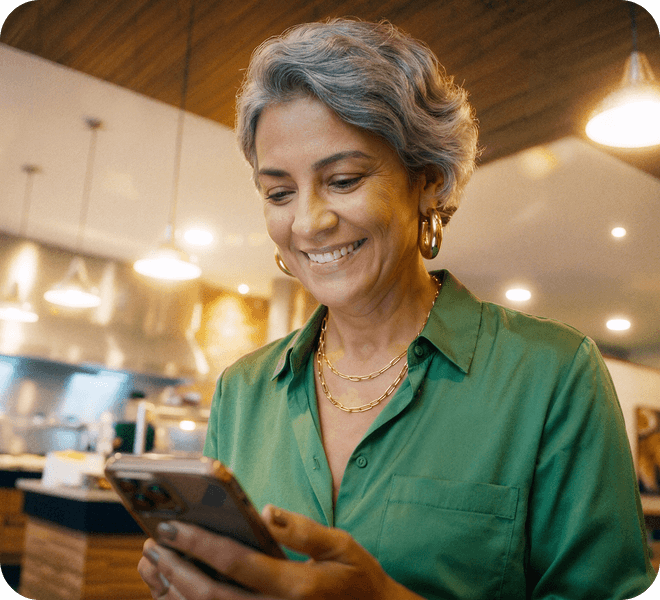 Mulher madura sorrindo e mexendo no celular