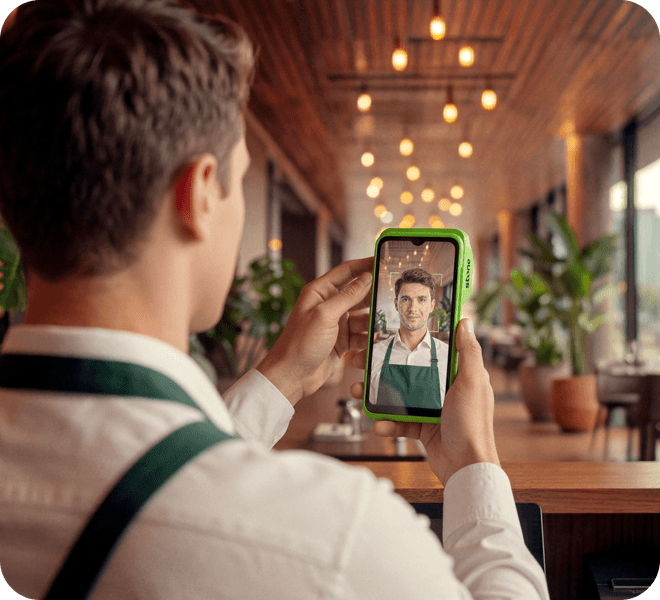 Garçom em restaurante usando o app Stone no celular para fazer uma chamada de vídeo com cliente
