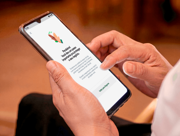 Mão segurando o celular com tela do Seguro Stone confirmando a contratação