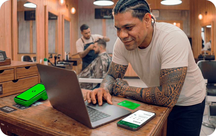 Funcionário em barbearia utilizando um computador junto com a maquininha stone