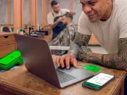 Funcionário em barbearia utilizando um computador junto com a maquininha stone