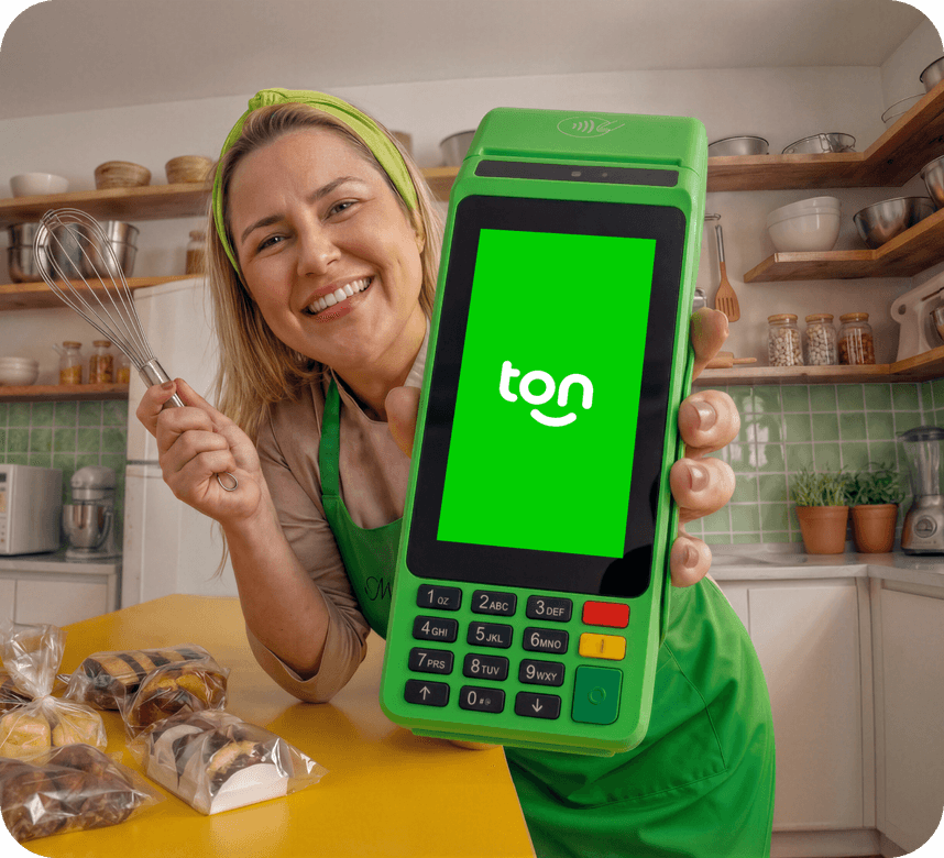 Mulher cozinheira sorrindo e segurando a a maquininha Ton