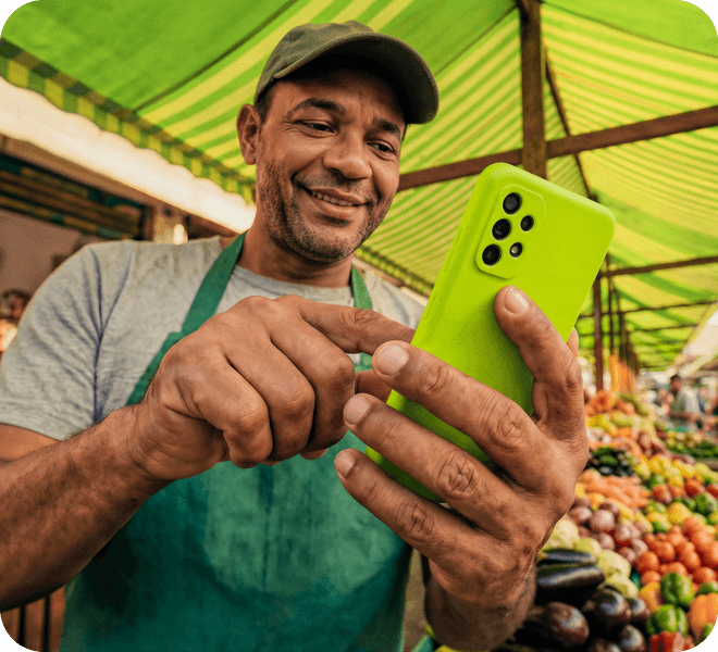 Feirante usando o app Ton no celular em sua banca