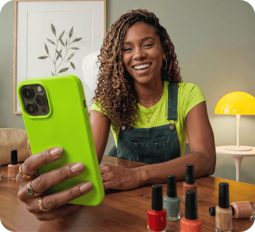 Empreendedora manicure sorrindo segurando o celular em seu salão