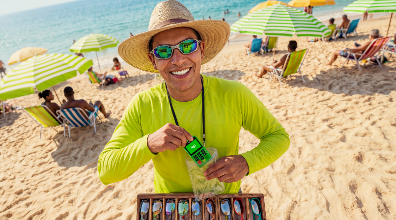 Homem sorrindo e vendendo óculos na praia 