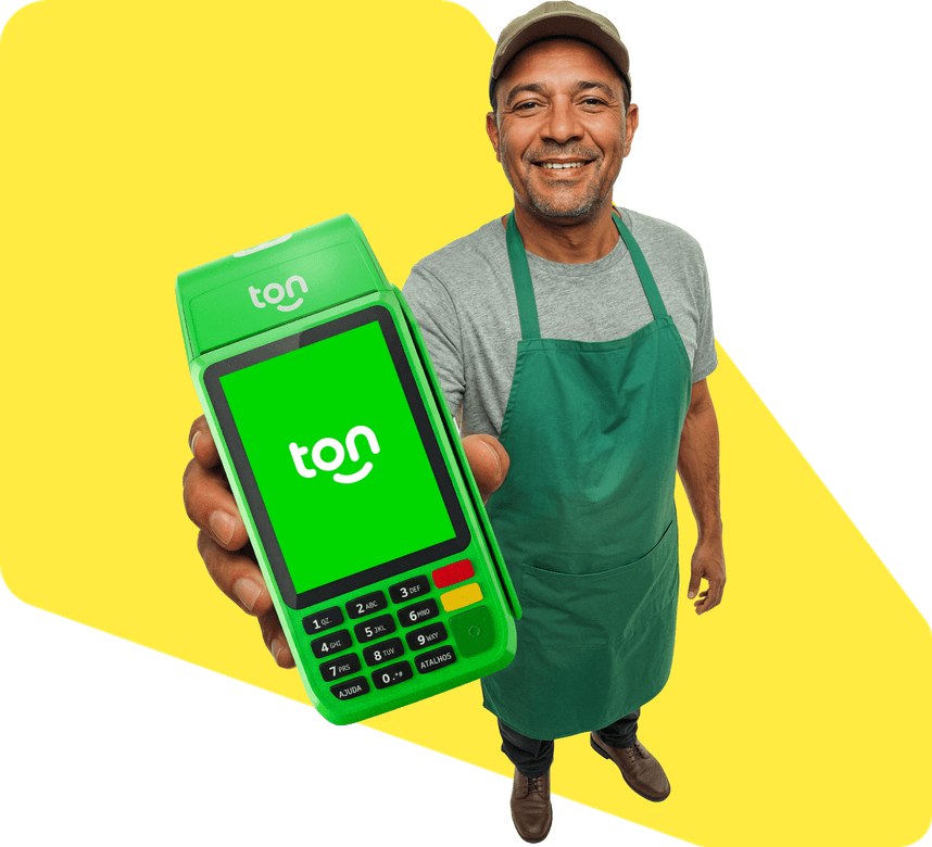 Empreendedor sorridente de avental verde segurando uma maquininha Ton.