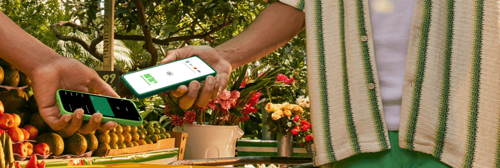 Empreendedor na sua barraca de laranja na feira com o seu celular recebendo o pagamento pelo Tapton, a maquininha no celular por aproximação do seu cliente.
