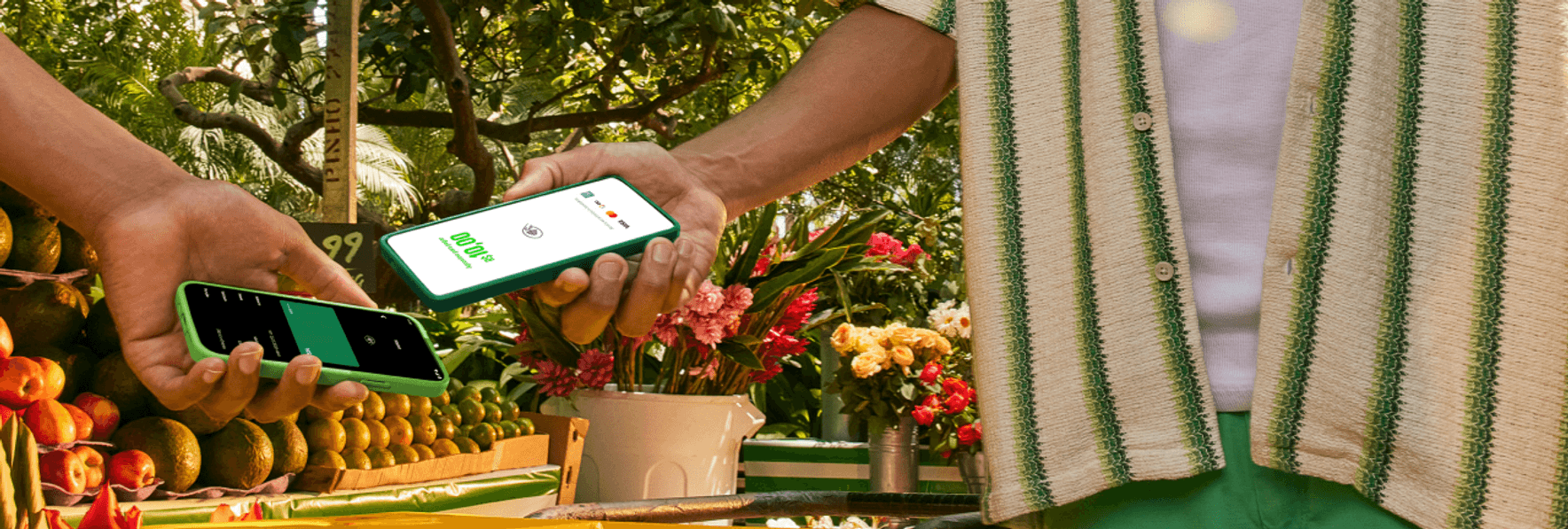 Empreendedor na sua barraca de laranja na feira com o seu celular recebendo o pagamento pelo Tapton, a maquininha no celular por aproximação do seu cliente.
