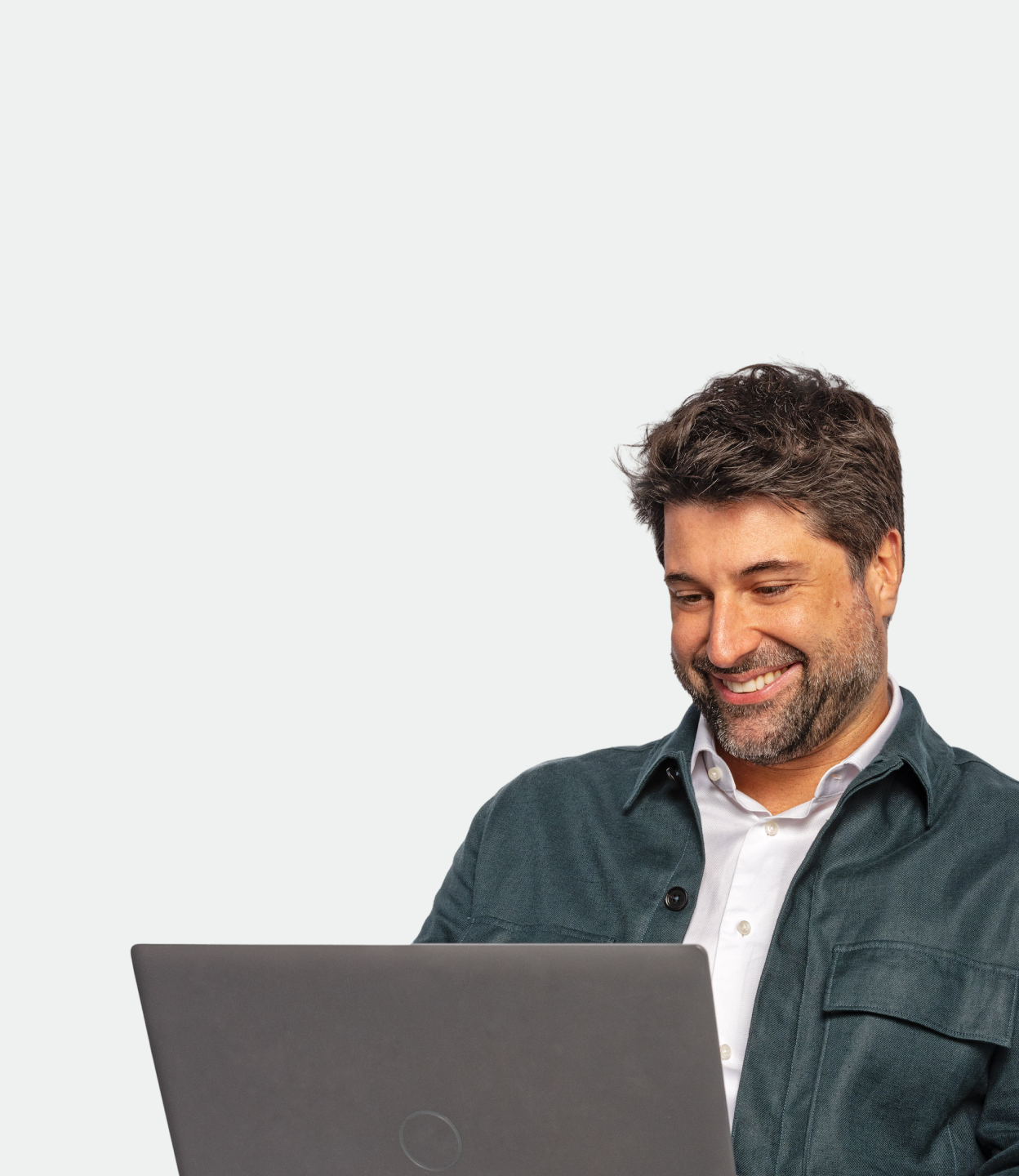 Pessoa de barba e jaqueta escura sorri enquanto usa um notebook.