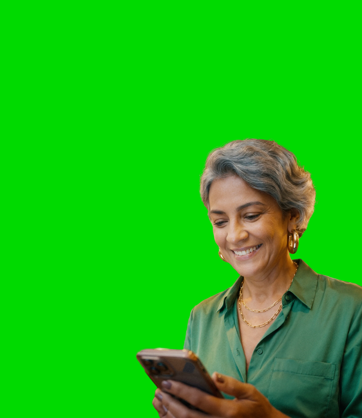 Pessoa de cabelo grisalho e camisa verde sorri enquanto confere algo no celular.