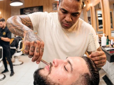 Barbeiro atendendo cliente em sua barbearia