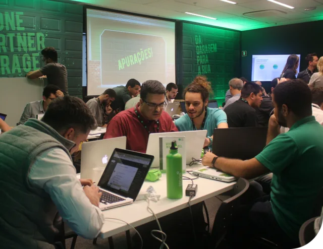 Rapaz da Stone de pé com microfone na mão fazendo uma fala para um escritório cheio