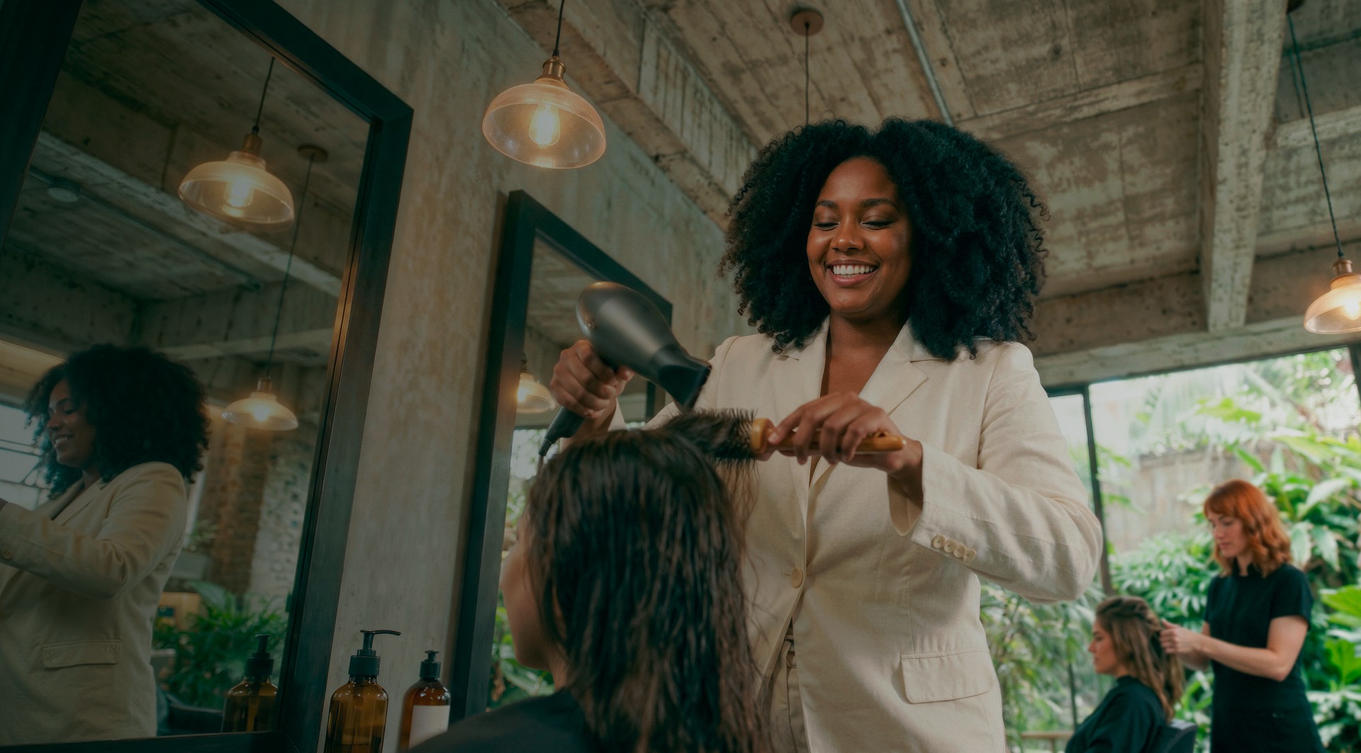 Cabeleireira sorridente escovando o cabelo de uma cliente em salão de beleza moderno