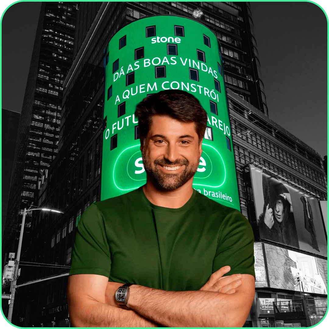 Homem sorrindo na frente de um prédio escrito stone