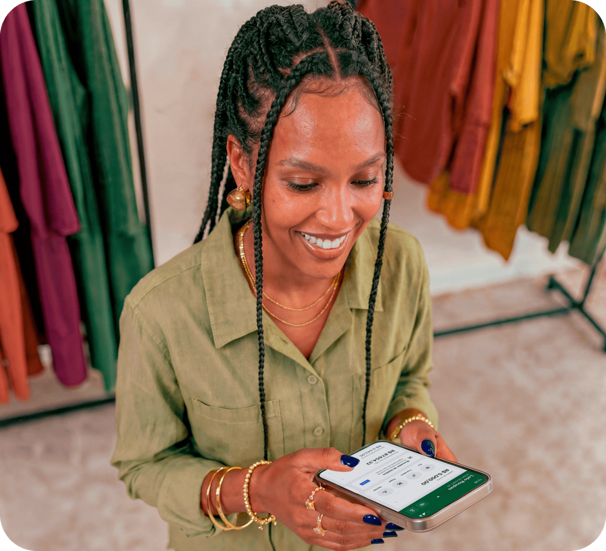 Empreendedora em loja de roupas sorrindo enquanto consulta o app Stone no celular