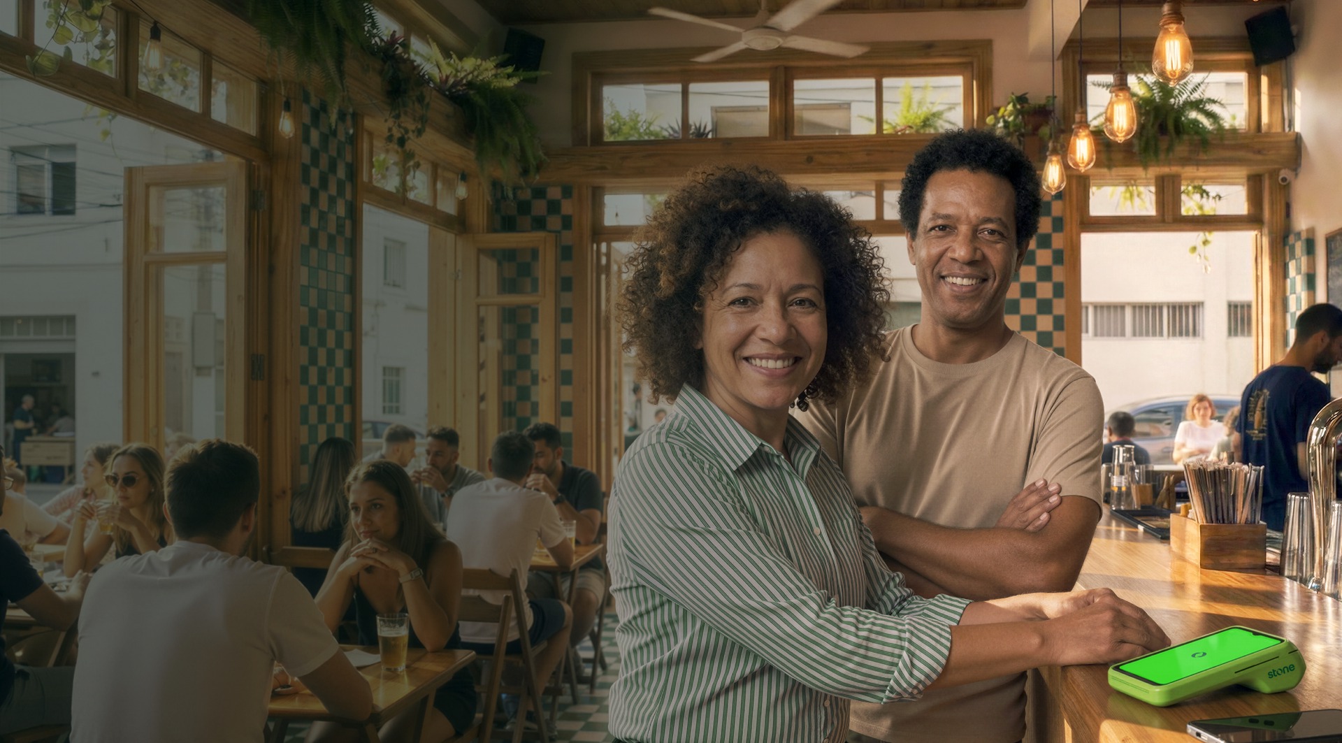 Empreendedores sorrindo em seu restaurante ao lado da maquininha Stone