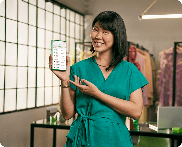 Empreendedora segurando o celular para utilizar o link de pagamento Stone em sua loja de roupas