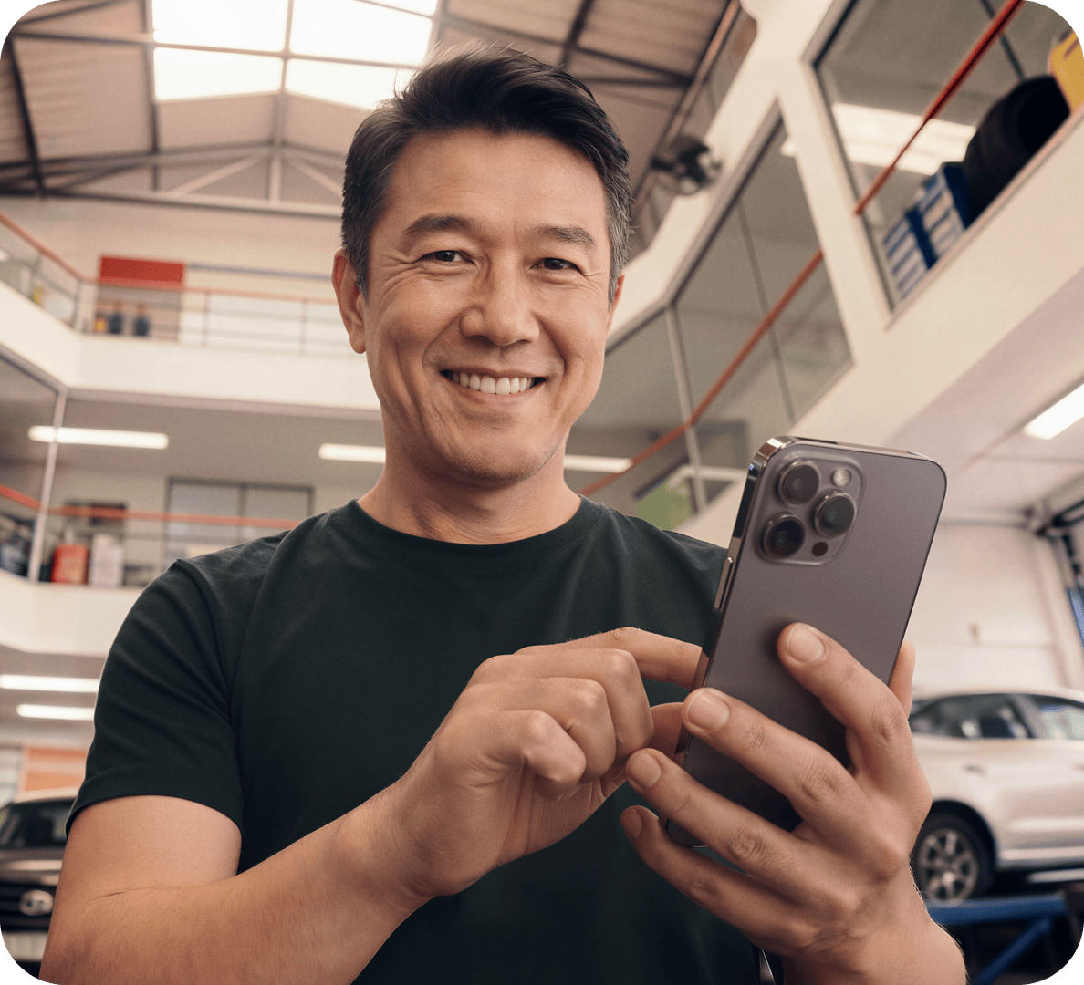 Mulher sorrindo, segurando a maquininha da Stone. Ao fundo, um computador na tela de dashboard da Conta Stone.