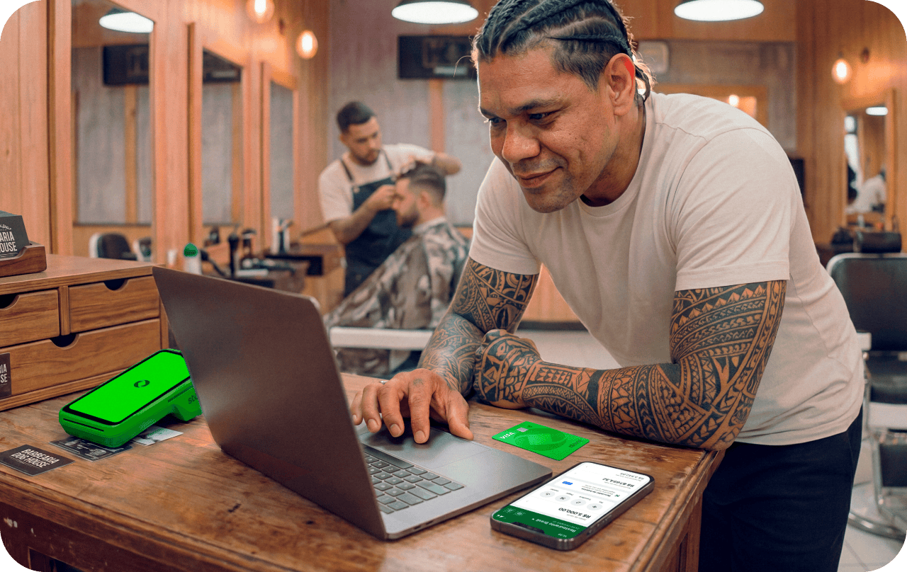 Funcionário em barbearia utilizando um computador junto com a maquininha stone