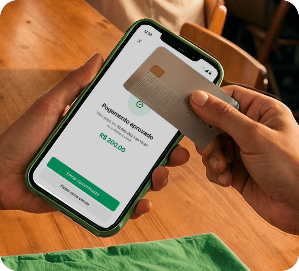 Venda feita pelo TapStone em um evento. Na esquerda, uma mulher de verde segurando o celular com TapStone e na direita, outra mulher segurando um cartão Stone para efetuar o pagamento.