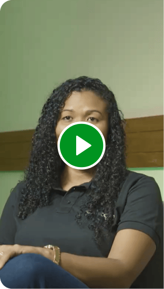 Consultora Renda Extra Ton. Mulher sorrindo, sentada em uma cadeira, rodeada por uma parede verde.