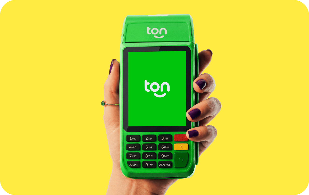 Mão segurando uma maquininha do Ton em um fundo verde